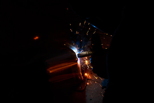 Arc welding. Welding pipes in inert gases. MIG / MAG. A bright flash of light and a sheaf of sparks.