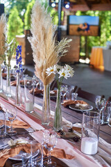 Wedding decoration. Floristics. Vessels with candles and bulk wax. Transparency and ease of design. Blue flowers and pampas.