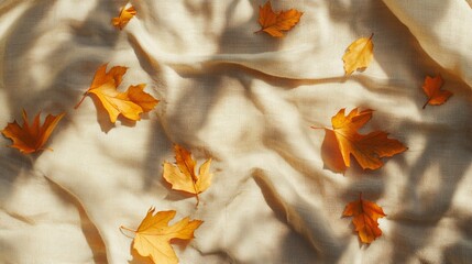 Autumn's golden embrace: vibrant maple leaves scattered across soft, creamy fabric, casting delicate shadows in warm sunlight. A serene composition of nature's artistry.