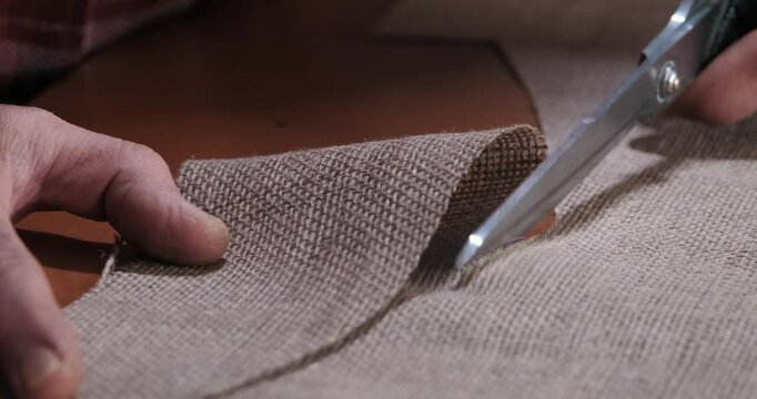 Close-up of hands cutting fabric with scissors showcases the delicate craftsmanship and artisan mastery of textiles, perfect for DIY and handmade projects.