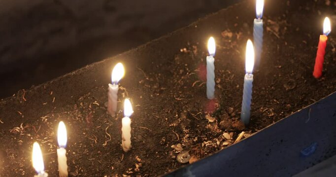 The camera moves as a candle lighting ritual is performed in an Alevi place of worship. The burning flames of the candles are clearly visible in the video.