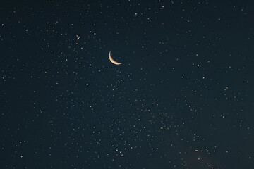 A crescent moon is shining brightly in the night sky
