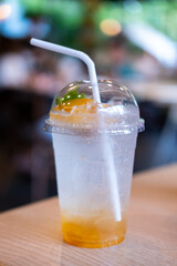 A cup of peach soda on the table, with bokeh background of the cafe