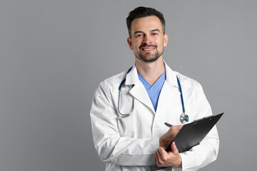 Smiling doctor with stethoscope and clipboard on grey background, space for text