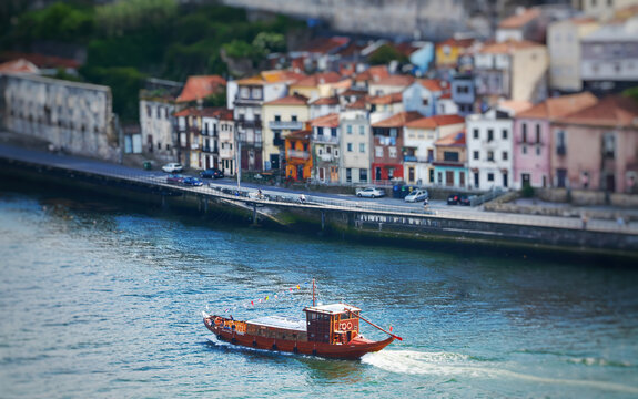 Tilt-shift photo of a traditional wooden barge on the river in Portugal.