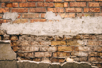 Old grungy brick wall. Free space for an inscription. Can be used as a background or poster. Fragment of a wall with bumps and shabby plaster.