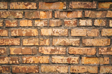 Old grungy brick wall. Free space for an inscription. Can be used as a background or poster. Fragment of a wall with bumps and shabby plaster.
