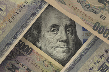 Portrait of the US President on the dollar bill peeks out from underneath the Japanese yen notes....