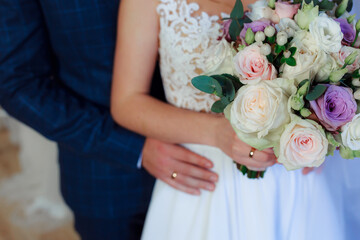 Wedding bouquet in the hands of the bride at the ceremony. Touching the hands of the bride and groom. Wedding jewelry. Wedding rings. The tenderness and beauty of the wedding ceremony.