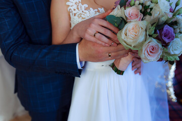 Wedding bouquet in the hands of the bride at the ceremony. Touching the hands of the bride and groom. Wedding jewelry. Wedding rings. The tenderness and beauty of the wedding ceremony.