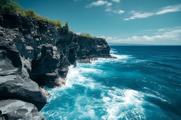 Obraz premium Incredible coastline where sheer rocky cliffs tower above the crashing waves of the deep blue ocean. Bright blue sky.