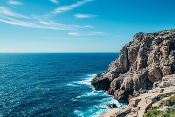 Obraz premium Incredible coastline where sheer rocky cliffs tower above the crashing waves of the deep blue ocean. Bright blue sky.