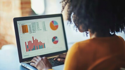 African American woman analyzing financial data on laptop screen