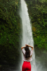 Young Woman Standing in Water Near a Powerful Waterfall.