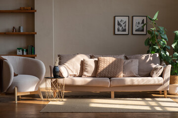 A stylish living room featuring a sofa and armchair, with plants and decor, creating a warm atmosphere
