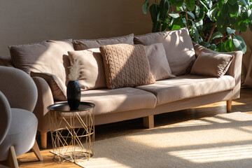 A serene living room scene featuring a couch and decorative items on a table, with sun lighting enhancing comfort.