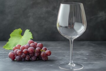 Empty Wine Glass and Red Grapes on a Gray Surface