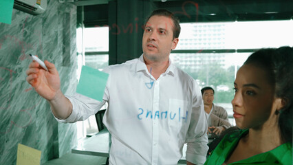 Skilled businessman presents marketing idea to project manager by using colorful sticky notes at...