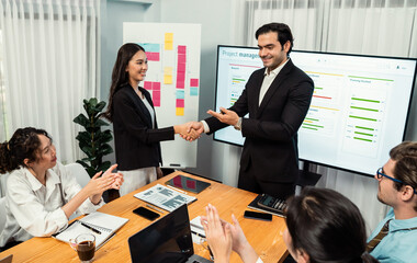 Proud boss or entrepreneur give credit and praise his employee with handshake after made successful sales or marketing plan to encourage and motivate group of diverse ethnic office workers. Habiliment