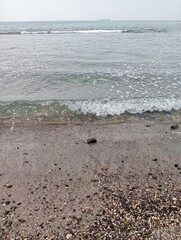 Portrait of waves, sand and small rocks on the beach