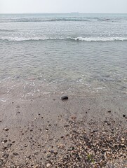 Portrait of waves, sand and small rocks on the beach