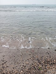 Portrait of waves, sand and small rocks on the beach