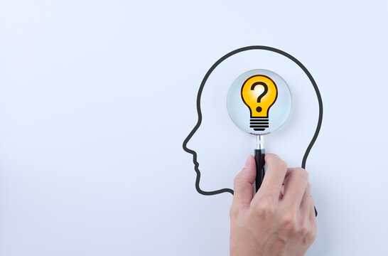 Idea discovery and inquiry concept. Hand holding a magnifying glass over question marks with light bulb, symbolizing idea discovery. Problem solving, Creative thinking, Company find business solution,
