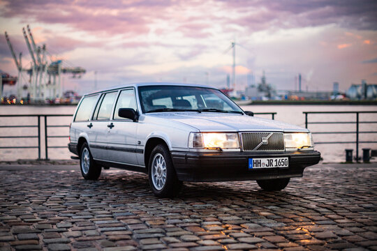 Hamburg, Germany, April 13, 2023: Silver Volvo 940 station wagon with cobblestones and harbor panorama, horizontal format