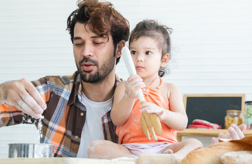 Cute Caucasian family, father smiling and teaching little daughter how to bake breads, learning to...