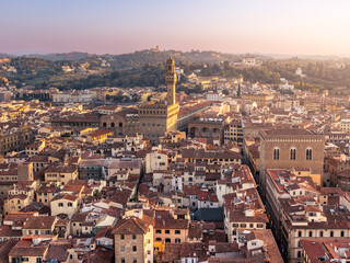 Obraz premium Cityscape of old city with high towers on palaces, tiled roofs in golden sunset light, Florence, Italy