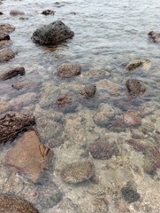Portrait of a beach scene on a sunny day with rocks on the shore