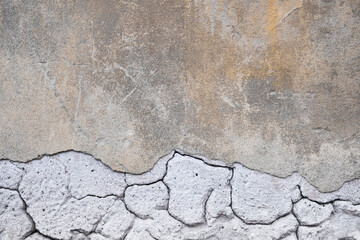 Cracked concrete wall covered with gray cement surface. Grey old wall with shabby damaged plaster or cement and brick background of an vintage dirty exfoliating plaster. Mock up.