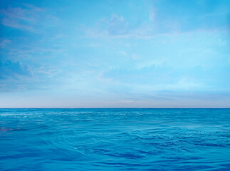 Obraz premium A deep blue sea and sky, clouds and a slight red color reflected in the clouds. There is no one in the empty sea and sky scene, suitable for montage and background