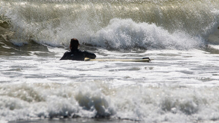 Surfer Navigating Powerful Waves at a Beach on a Sunny Afternoon