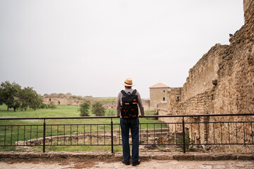 Retired man touring ancient fortress, marveling at cultural history and heritage, enjoying quiet sightseeing through ancient ruins on a peaceful day out.