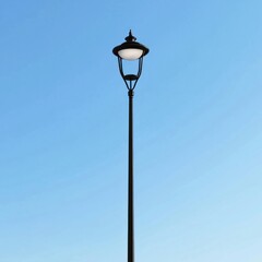 A tall street lamp with a single curved light fixture, standing against a clear blue sky, isolated...