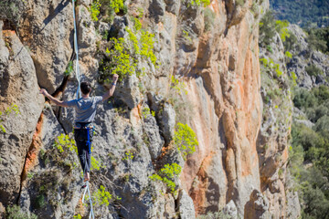 A tightrope walker walks along a cable stretched over a canyon.