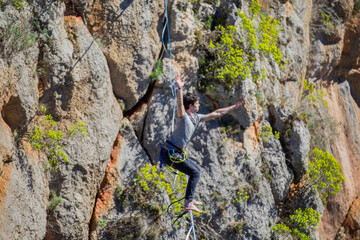 A tightrope walker walks along a cable stretched over a canyon.