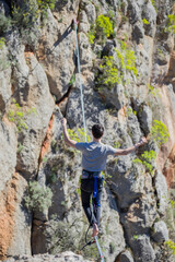 A tightrope walker walks along a cable stretched over a canyon.