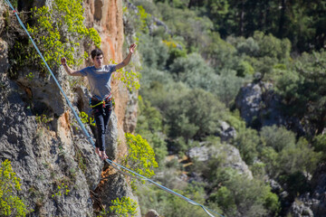 A tightrope walker walks along a cable stretched over a canyon.