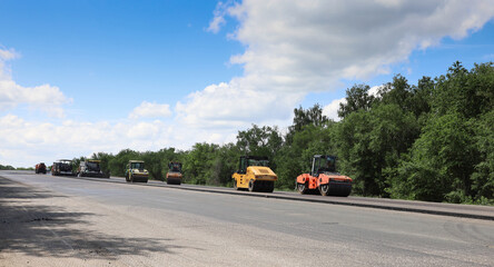 A group of construction vehicles are lined up on a road