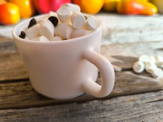 Coffee cup with coffee beans and marshmallows on the table