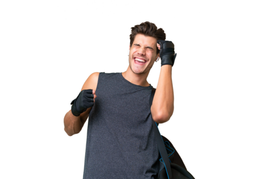 Young sport caucasian man with sport bag over over isolated background celebrating a victory