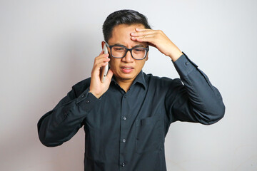 Asian man feeling dizzy while receiving a call wearing casual clothes isolated on white background
