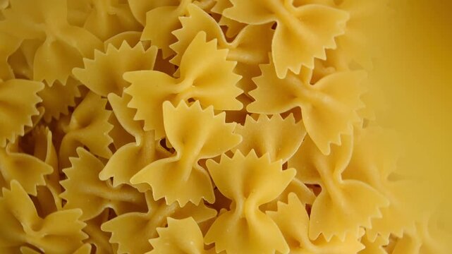 Raw farfalle pasta, swirled and sprinkled on top. Pasta in the form of butterflies or bows. View from above.
