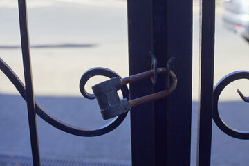 black metal forged gates closed with padlock.