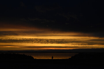 Person watching sunset in the coast ocean sea