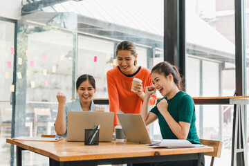 Excited women celebrating success while working together in modern office. Their teamwork and enthusiasm create positive and motivating atmosphere