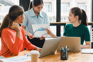 Obraz premium Collaborative business meeting with three women discussing financial charts and data analysis. atmosphere is focused and professional, highlighting teamwork and communication