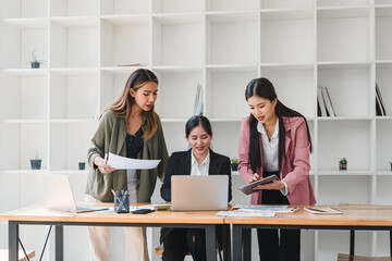 Collaborative business meeting with three women discussing project details at modern office desk. They are engaged and focused, showcasing teamwork and professionalism